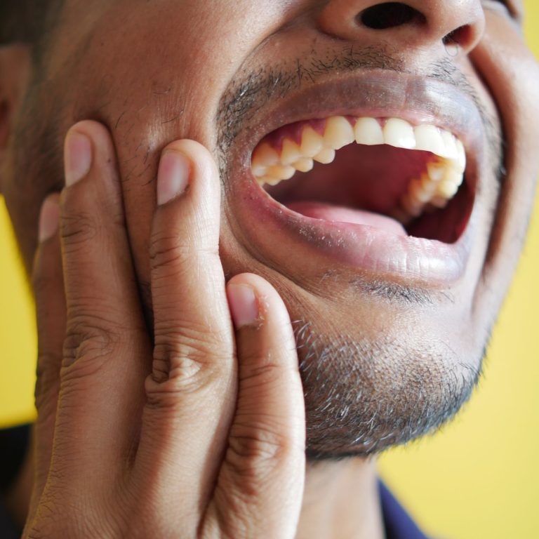 Person holding a knocked out tooth in a tissue, showing what to do when a knocked out tooth occurs